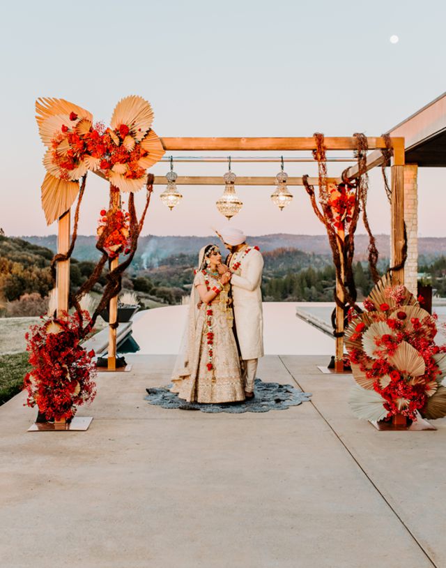 Couple stands under a modern indian wedding arbor